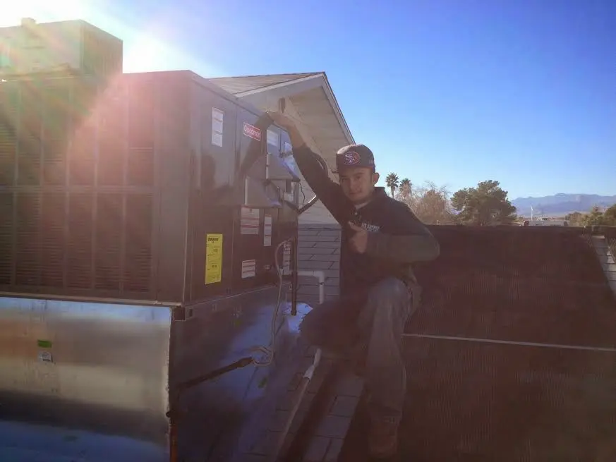 HVAC technician performing Air Duct Cleaning on a rooftop unit in Lamont